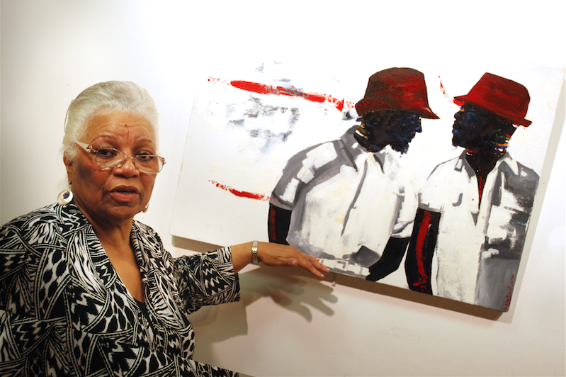 Museum director Joysetta Pearse stands before a canvas created by Oluwatoyin Tella, a Nigerian-born painter living in Hempstead. (Spencer Rumsey/Long Island Press
