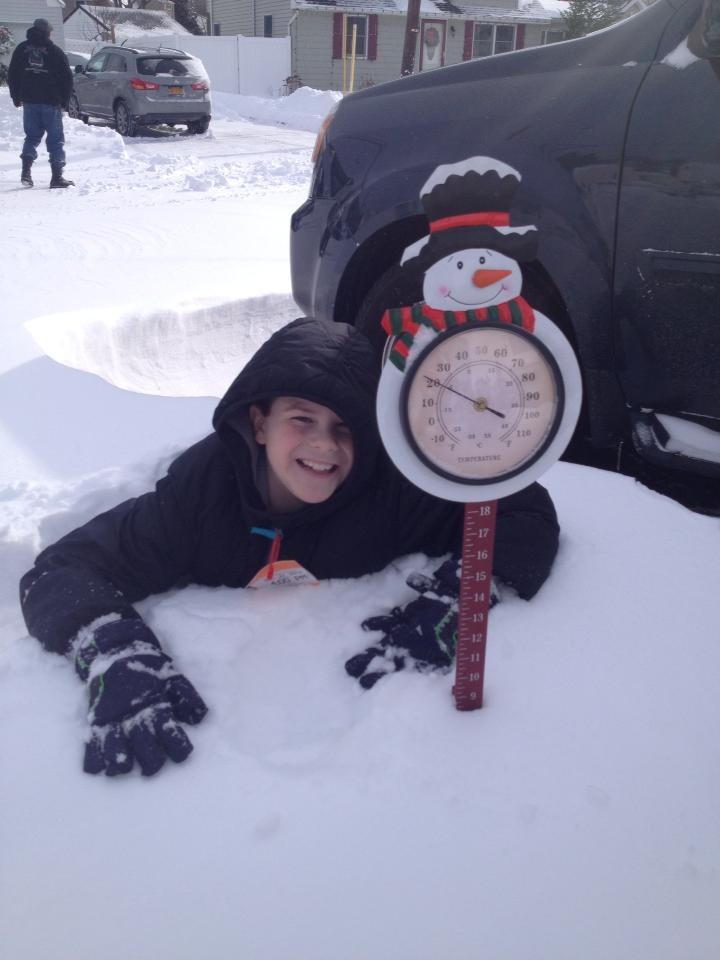 Nine-year-old Kevin measures and takes temperature of the snow piled up in front of his North Babylon home on Friday, Jan. 3, 2014. (Photo credit: Send in from reader)