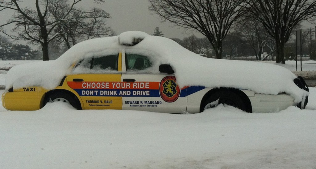 A Nassau County police vehicle at Eisenhower Park in East Meadow is covered in snow from the latest storm that hit LI. (Timothy Bolger/Long Island Press) 