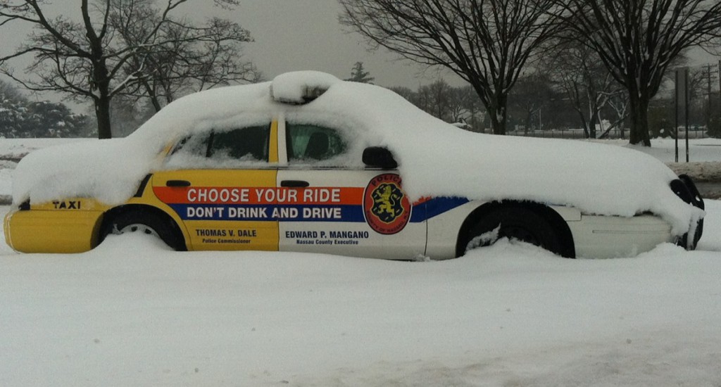 A Nassau County police vehicle at Eisenhower Park in East Meadow is covered in snow from the latest storm that hit LI. (Timothy Bolger/Long Island Press)
