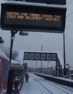 A woman waits for a Long Island Rail Road train on the snow-covered Bay Shore station platform under an electronic sign explaining why the waiting rooms are open later than usual during a storm Monday, Feb. 3, 2014.