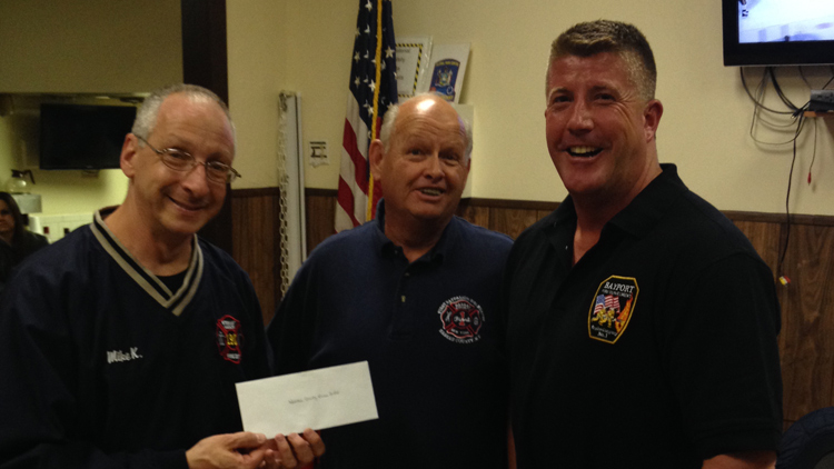 Ray Cooney (far right) presents a check from the proceeds of his TV show Firehouse Kitchen to the Nassau County Burn Center during a recent Nassau County Fire Commissioners meeting in Floral Park. Here he is accompanied by Firefighter Mike Kusher (left) and Floral Park Fire Department Commissioner Ken Fairben (center).