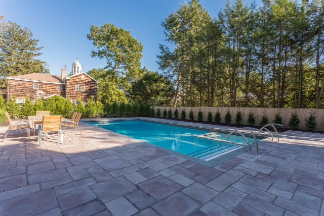 The backyard features an inground heated gunite pool with Jacuzzi outdoor kitchen and entertainment area bluestone slate patio.