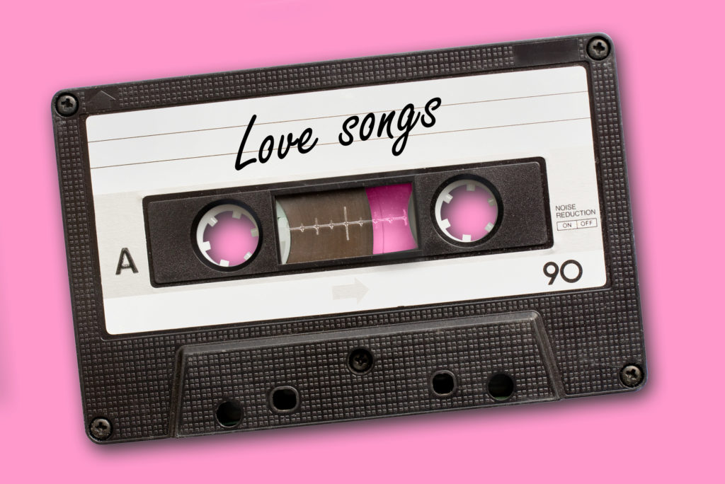 Love songs written on vintage audio cassette tape, pink background