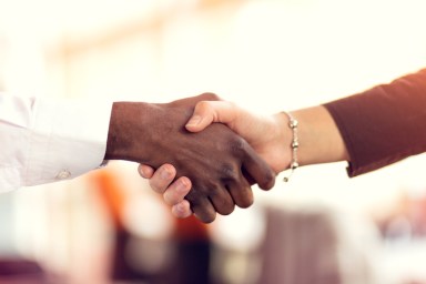 Closeup of White and Black shaking hands over a deal