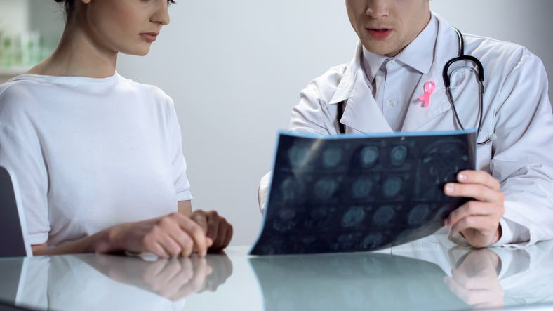 Male doctor explaining young lady results of mammogram, breast cancer awareness