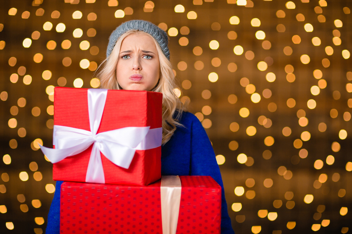 Woman holding gift boxes over holidays lights background