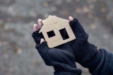 young homeless boy holding a cardboard house