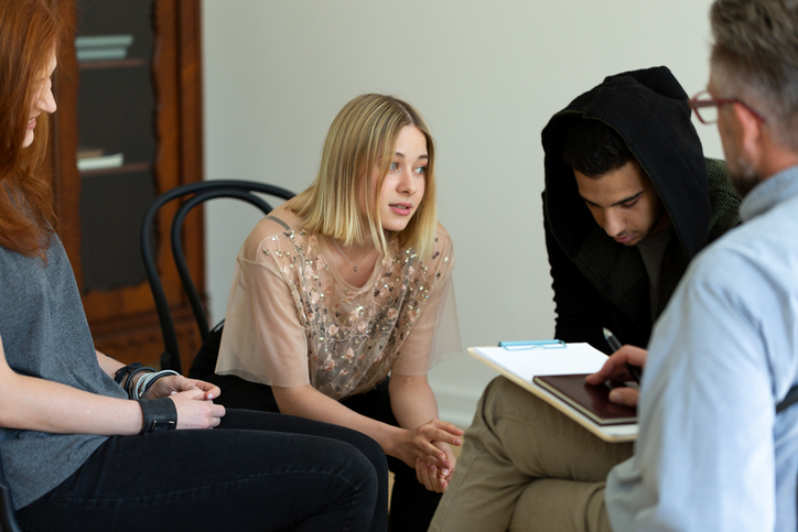 Teenage girl talking with psychologist during meeting of support group