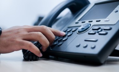 close up employee man hand point to press button number on telephone office desk for contact customer or colleagues in company .hotline employee concept