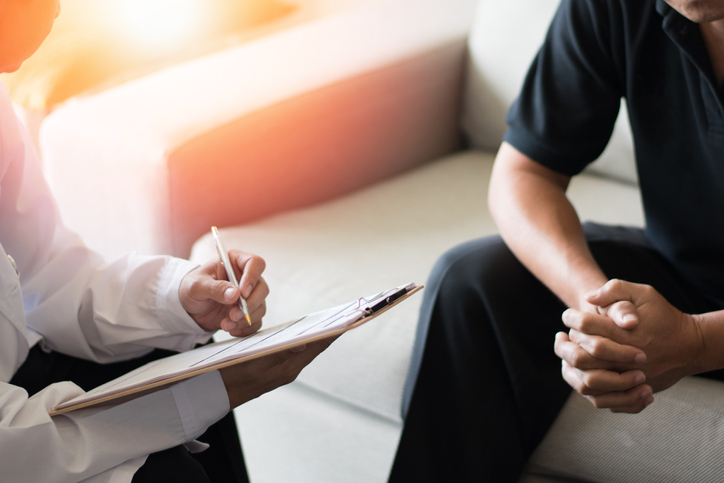 Doctor physician consulting with male patients in hospital exam room. Men’s health concept.