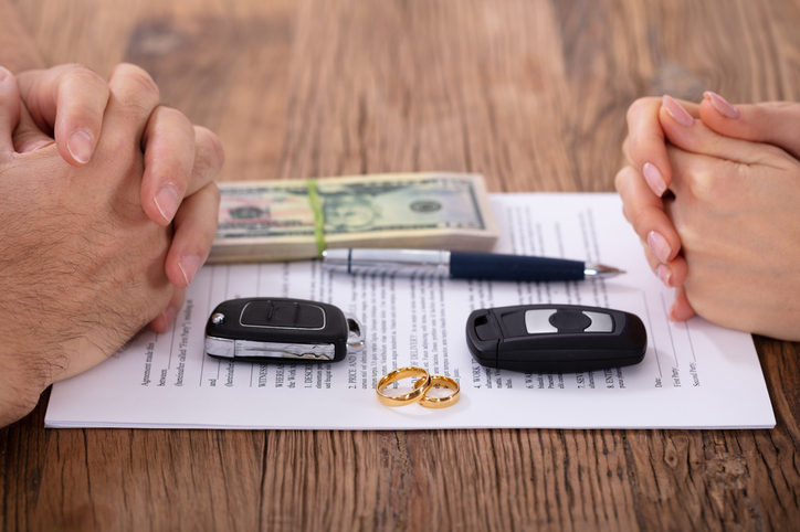 Hands On Divorce Document With Wedding Rings And Car Keys