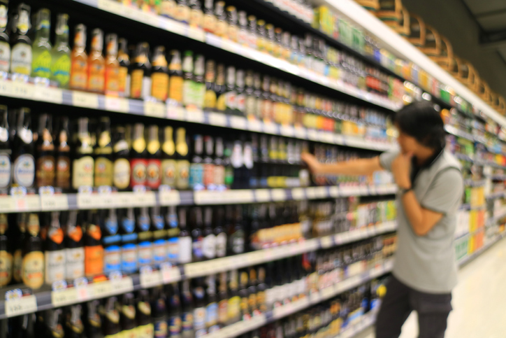 Out of focus shot of a man looking at the goods on grocery shelf in a retail store