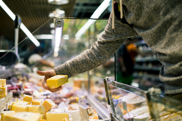 close up person hand buying cheese in  store