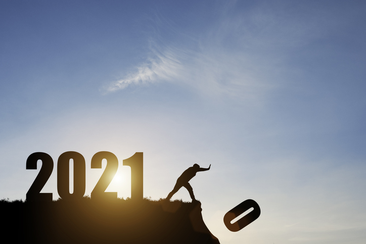 Man push number zero down the cliff where has the number 2021 with blue sky and sunrise. It is symbol of starting and welcome happy new year 2021.