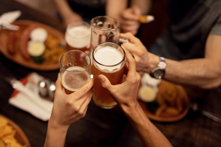 Close up of friends toasting with beer and having fun in a pub.