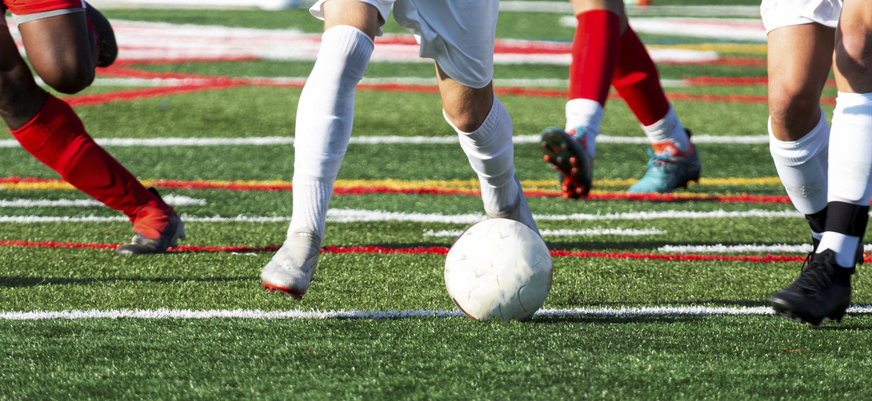 Legs of soccer players chasing ball during game
