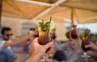person raising and chinking with a long island ice tea cocktail.