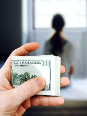 Man holds in his hand a bundle of one hundred dollar bills against the background of the girl who they are going to sell into slavery. The concept of violence, human trafficking. Mixed media