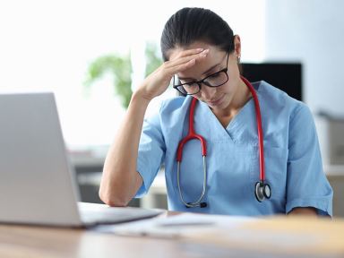 Tired doctor sitting at table and holding his head