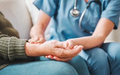 Shot of a nurse checking the pulse of her elderly patient