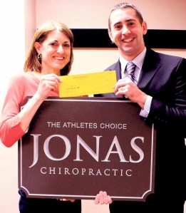 Dr. Jonathan DeGorter of Jonas Chiropractic & Sports Injury Care presents the sponsorship check to Race Director Karen Schackner.