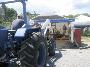 Ed Peterson drives the forklift into the shed where Bill Shephard is directing placement of the black walnut plank, as Jim Brannigan (right) oversees the move. (Photos by Dagmar Fors Karppi)