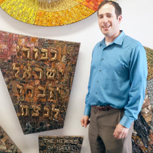 New JJC rabbi, Ben Herman, in front of a stone sculpture in his Tucson synagogue. Plaque reads, in Hebrew, “The heroes of Israel shall never be forgotten.”