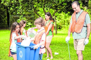 Volunteers: Family cleans up their community park. Recycling bin.