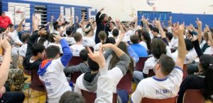 When participants raise their hands in the air as they are doing in this photo, using the sign language sign for ‘I love you,’ they are expressing solidarity with fellow students and colleagues.