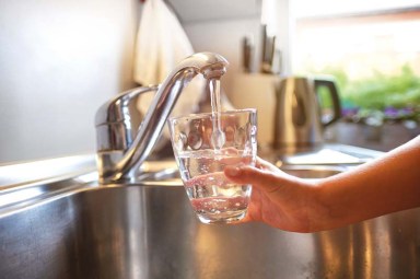 Close up of children hands, pouring glass of fresh water from tap in kitchen