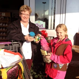 Port Resident handing canned food donations to a Brownie Troop #443 member