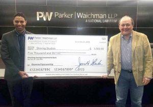 Kyle Savage of Shining Studios receives a check for $5,000 from Jerrold Parker of Parker Waichman, LLP.