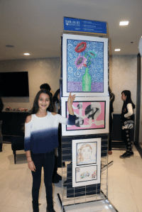 Great Neck North Middle School student Ariela Hakimi proudly points to her artwork.
