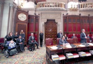 Jack Martins, standing right, leads the state senate in honoring John Kemp, seated third from left.