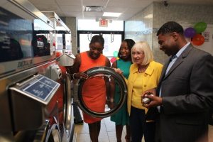 Nassau County legislator Siela Bynoe, Councilwoman Viviana Russell and Town Supervisor Judi Bosworth check out the new machines at the laundromat owned by XXXXX