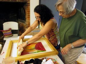 Stephanie Navon-Jacobson demonstrates how to pull a silkscreen monotype print as student Barbara Flamm looks on at The Art Guild at Elderfields Historic Preserve, Manhasset, NY.