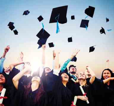 Smiling students throwing graduation caps in air