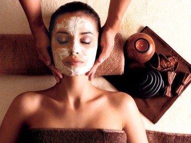 Woman with facial mask getting massage at spa