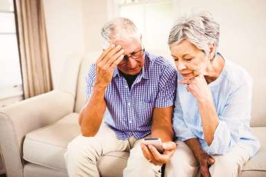 Sad senior couple looking at mobile phone