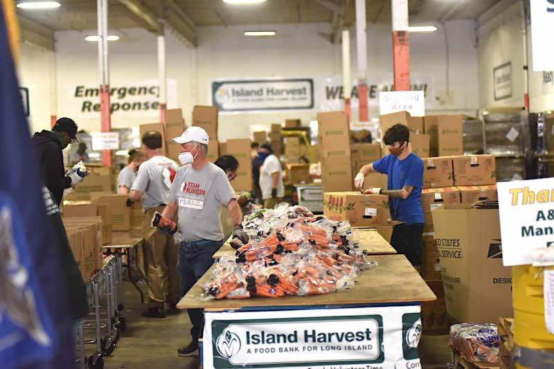 Volunteers are shown on June 29 at an Island Harvest warehouse, putting together some of the 4,000-plus boxes for a massive food distribution effort on July 1.