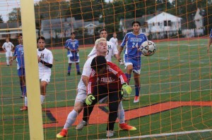 Hicksville’s Matt Sloan pressures Herricks goalie Cleber Guamann in the Sep. 28 game. Guamann could not hold on to this direct kick by Storm Strongin in Hicksville’s 1-0 win. Hicksville’s Michael Constantinescu (left) and Jason McMullan (just over Sloan’s shoulder) watch, along with Herrick’s Luke Laurino (24). (Photo by Frank Rizzo)
