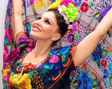 beautiful smiling mexican woman in traditional mexican dress nands up holding the skirt as a background like peacock