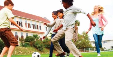 Energetic school children playing football, outdoors
