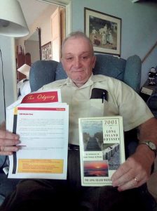 President Dennis Kotch holds a copy of the Guild’s newsletter The Odyssey in one hand and 2001–A Long Island Odyssey, a collaborative effort on the part of members of the Guild.