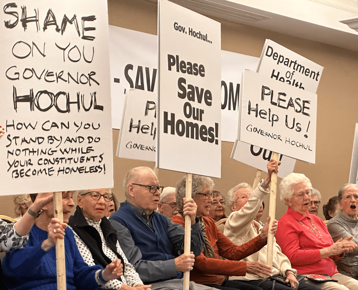 Residents of The Harborside holding signs protesting the state's denial of a prior sale