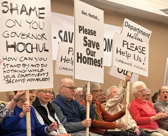 Residents of The Harborside holding signs protesting the state's denial of a prior sale