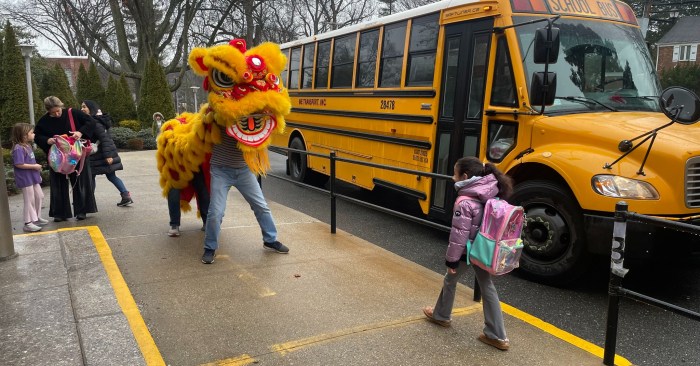 A student is greeted at Saddle Rock Elementary by a lion dancer
