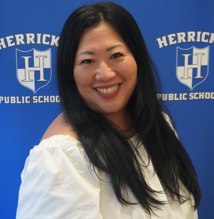 Herricks board president standing in front of a blue background.