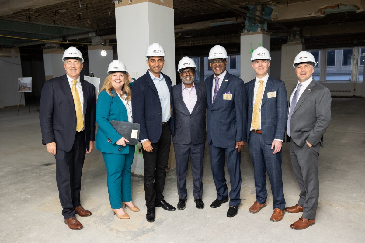 Adelphi team members standing in hard hats at the groundbreaking of a new campus.